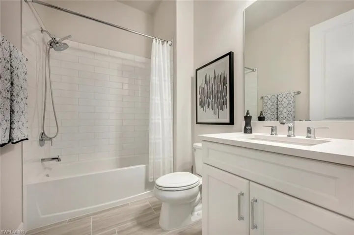 Full bathroom featuring shower / bathtub combination with curtain, tile flooring, vanity, and toilet