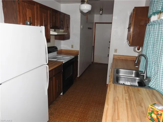 Kitchen featuring white appliances, sink, and dark brown cabinetry