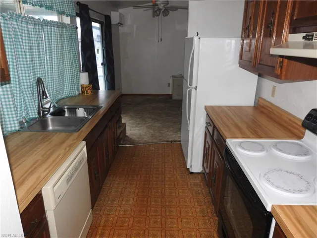 Kitchen featuring range hood, wood counters, white appliances, sink, and ceiling fan