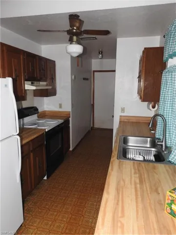 Kitchen featuring fridge, range hood, sink, ceiling fan, and range