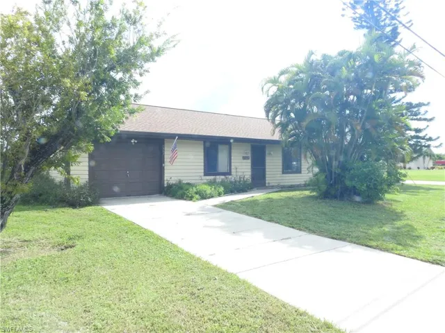 Single story home featuring a garage and a front lawn
