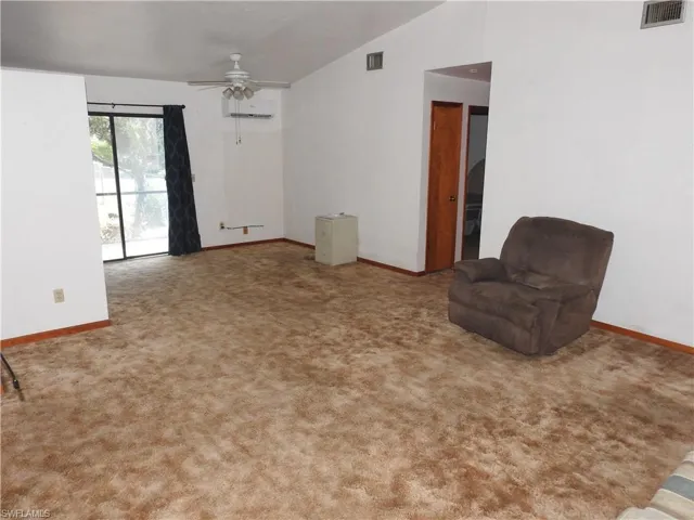 Unfurnished room with lofted ceiling, ceiling fan, light carpet, and an AC wall unit