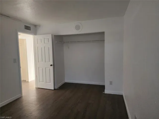 Unfurnished bedroom with dark wood-style floors and a closet