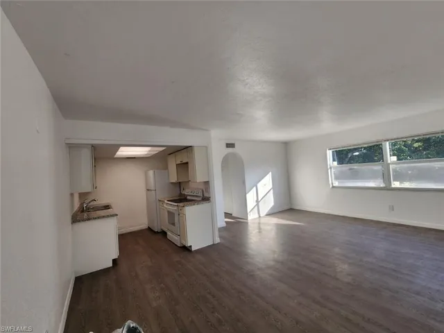 Kitchen featuring electric stove, arched walkways, dark wood-type flooring, and open floor plan