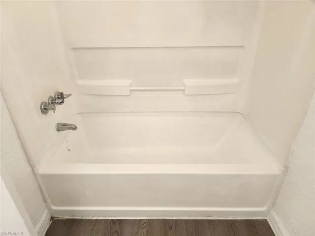 Bathroom with wood finished floors and tub / shower combination