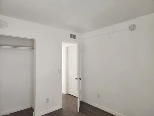 Unfurnished bedroom with dark wood-style floors and a closet