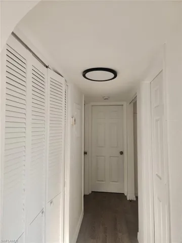 Corridor with dark wood-style floors and baseboards