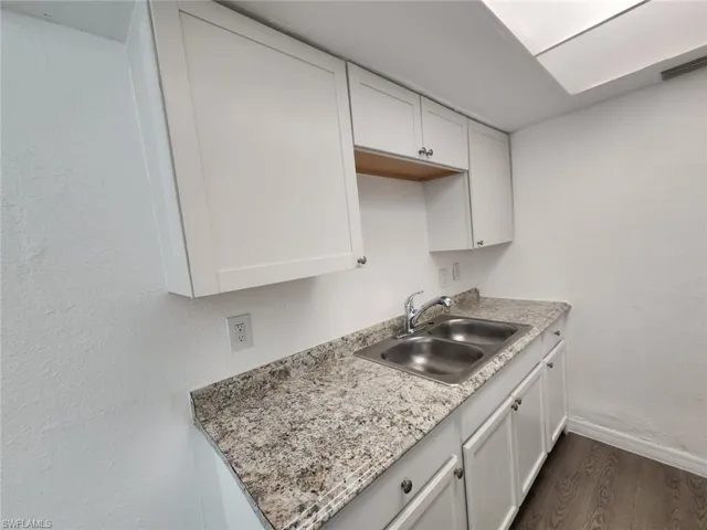 Kitchen featuring light countertops, white cabinetry, and dark wood-type flooring
