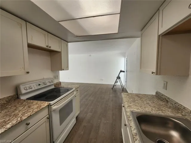Kitchen featuring white electric range, dark wood-style floors, and light stone countertops