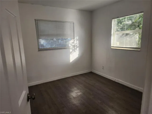 Empty room featuring dark wood finished floors and a textured wall