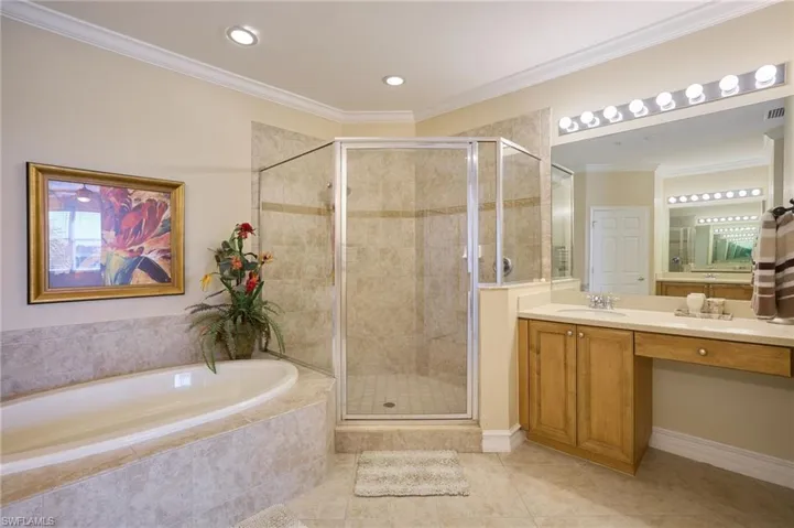 Bathroom featuring vanity, tile patterned flooring, ornamental molding, and shower with separate bathtub