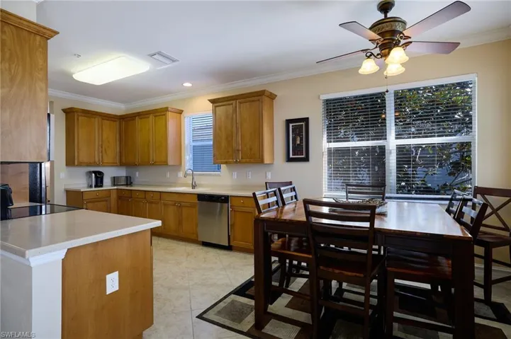 Kitchen featuring light tile patterned flooring, sink, black electric cooktop, stainless steel dishwasher, and ornamental molding