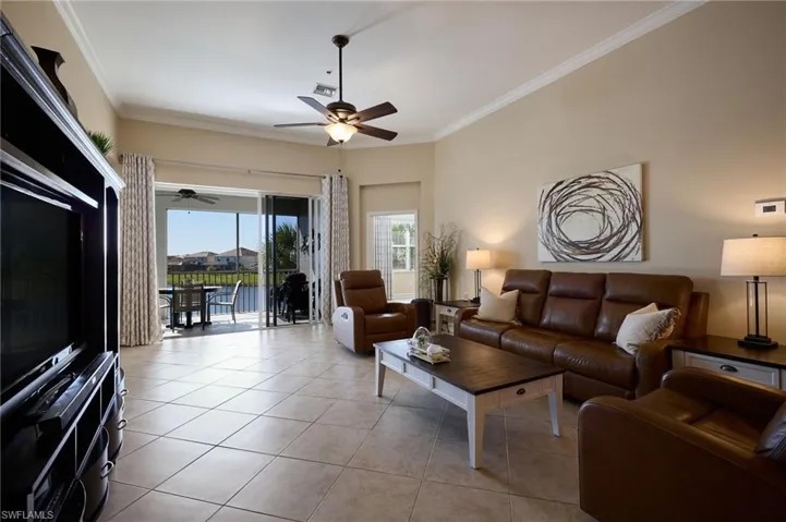 Tiled living room featuring ceiling fan and ornamental molding