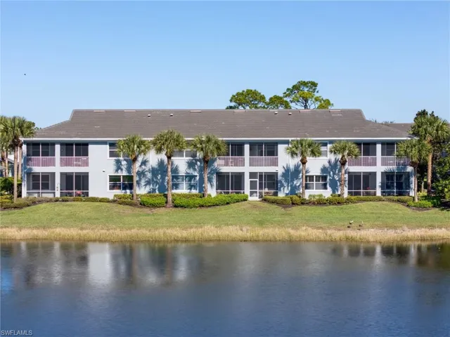 Rear view of property featuring a water view and a lawn