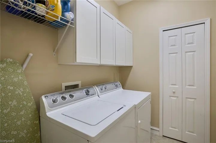 Laundry area with light tile patterned flooring and separate washer and dryer