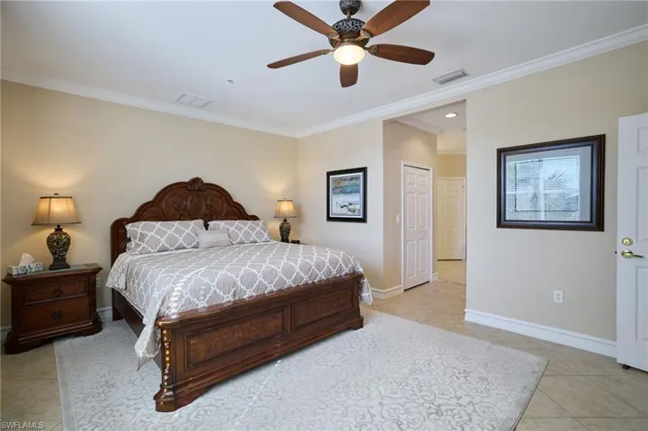 Bedroom with light tile patterned floors, crown molding, and ceiling fan