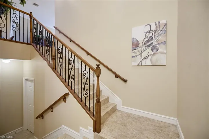 Staircase featuring tile patterned flooring leading to storage room and garage downstairs and main living area upstairs