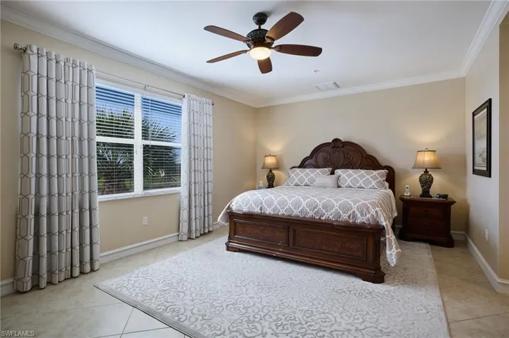 Bedroom featuring ornamental molding, light tile patterned floors, and ceiling fan