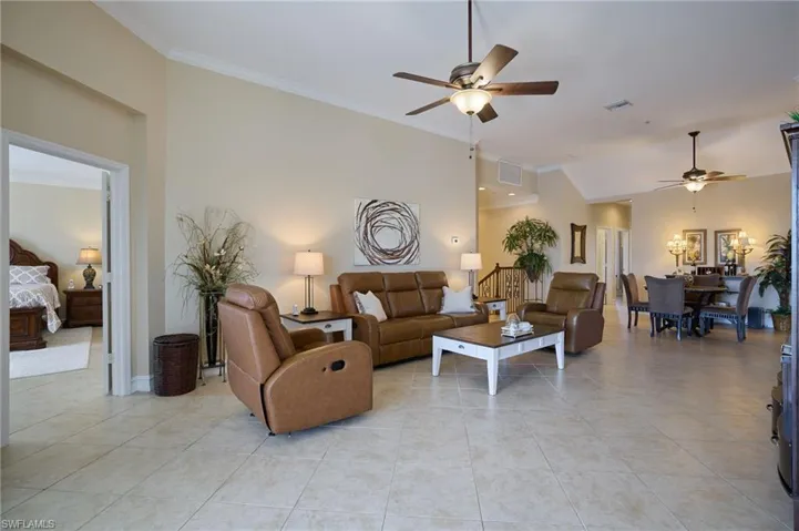 Living room featuring ornamental molding, lofted ceiling, light tile patterned flooring, and ceiling fan