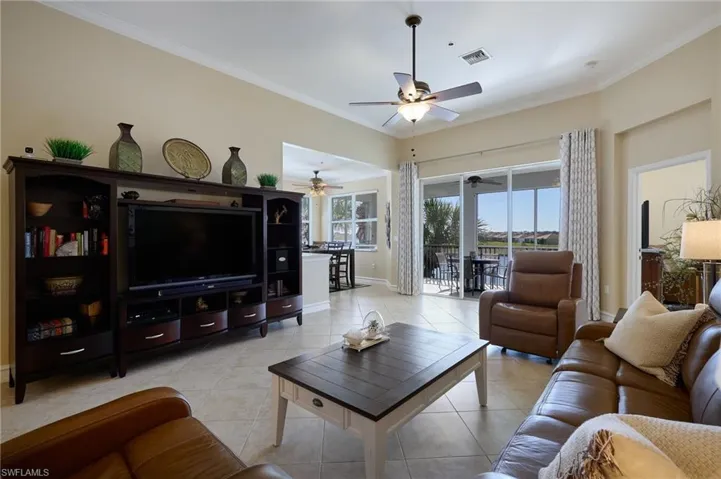 Living room featuring ceiling fan, ornamental molding, and light tile patterned floors