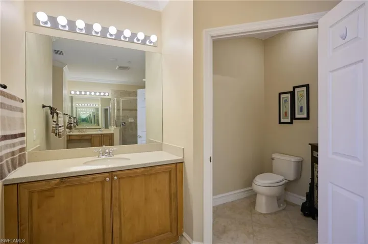 Bathroom featuring toilet, crown molding, vanity, a shower with door, and tile patterned flooring