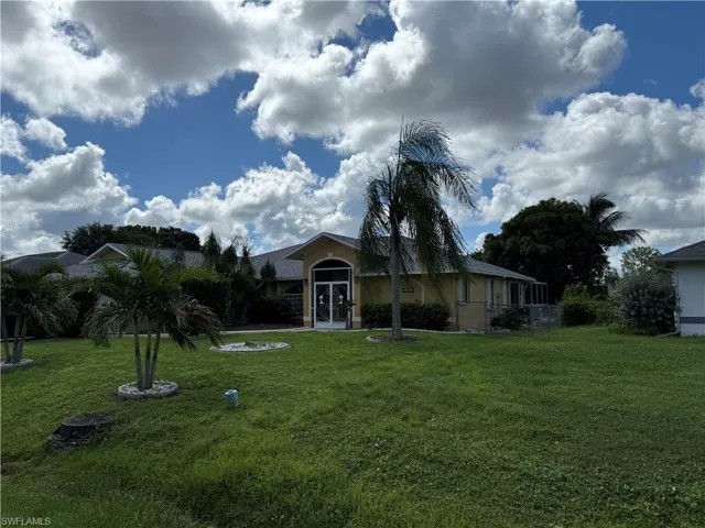 View of front of property with a front yard, stucco siding, and a sunroom