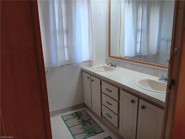 Bathroom with double vanity and baseboards