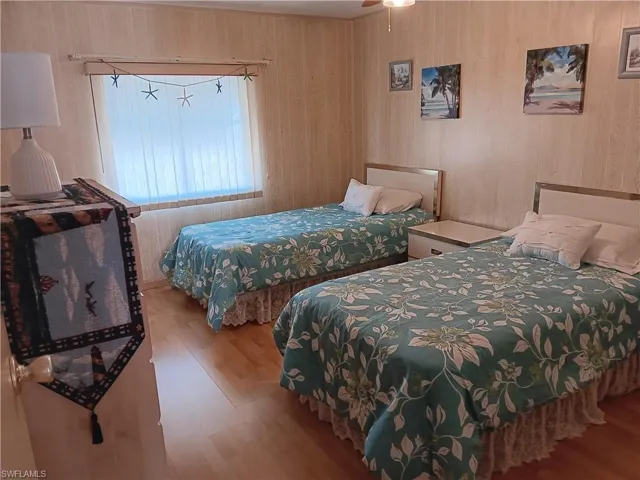Bedroom featuring wood finished floors and wood walls
