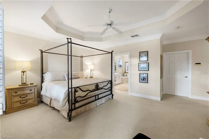 The spacious primary suite features an elegant tray ceiling, plantation shutters, a generous walk-in closet, and a beautifully appointed sitting area.