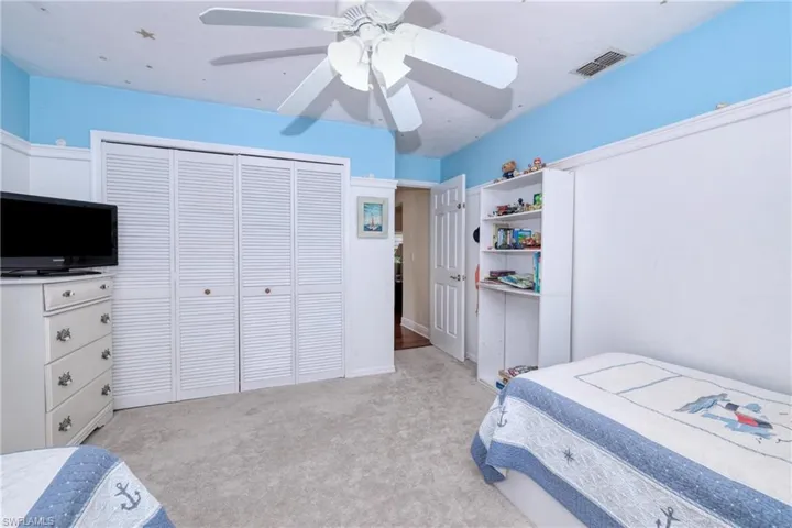 Bedroom with a closet, ceiling fan, and light carpet