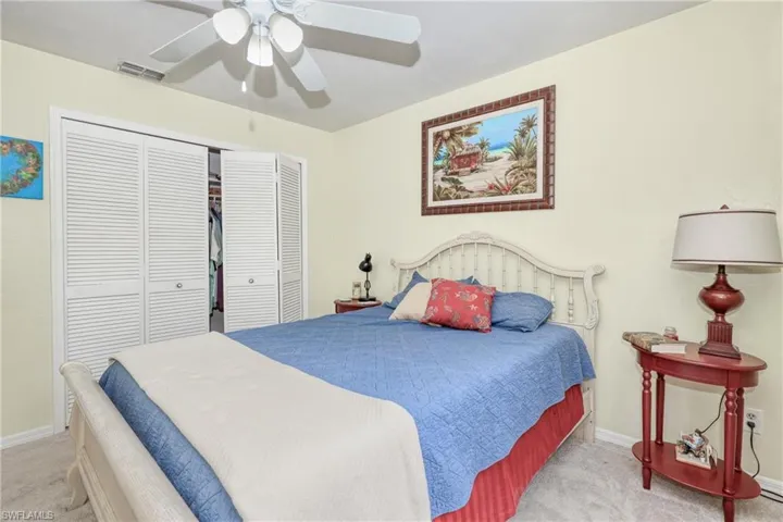 Carpeted bedroom with ceiling fan and a closet
