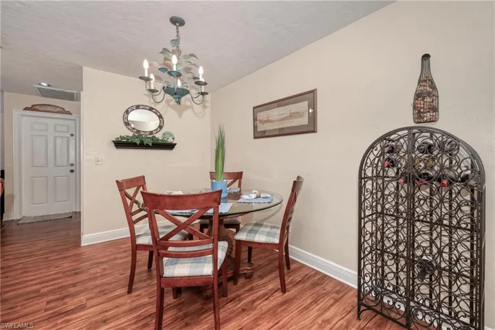 Dining room with a textured ceiling, dark wood-type flooring, and a chandelier