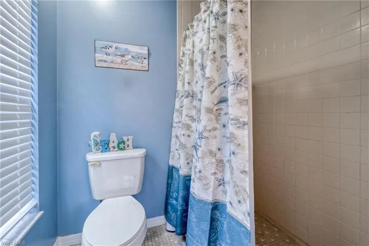 Bathroom with a shower with curtain, toilet, and tile patterned flooring