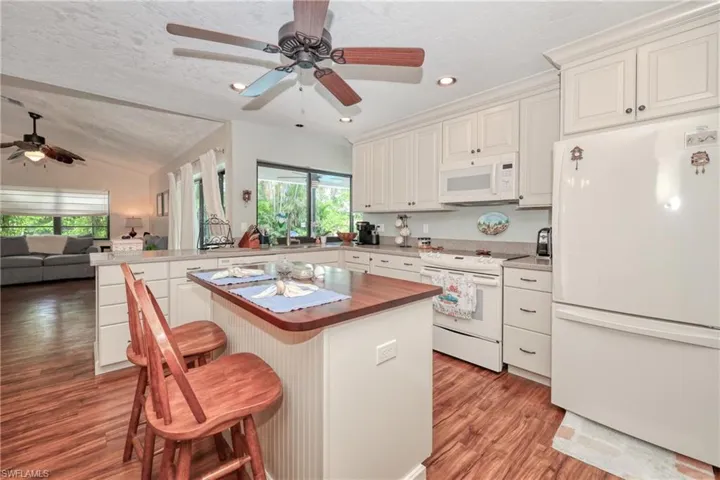 Kitchen featuring white appliances, a kitchen breakfast bar, plenty of natural light, a kitchen island, and ceiling fan
