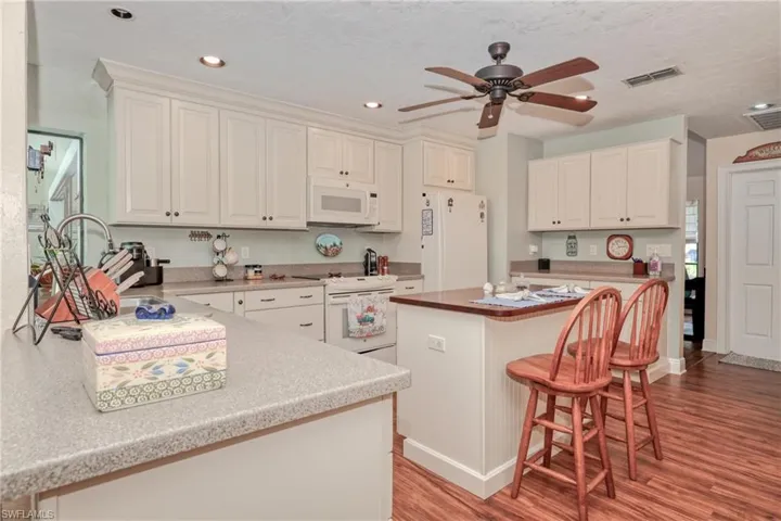 Kitchen with white appliances, a center island, light hardwood / wood-style floors, and ceiling fan