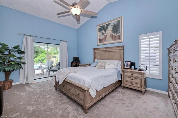 Carpeted bedroom featuring vaulted ceiling, access to exterior, and ceiling fan