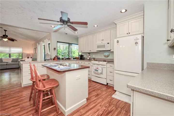 Kitchen featuring a kitchen breakfast bar, white appliances, plenty of natural light, and ceiling fan