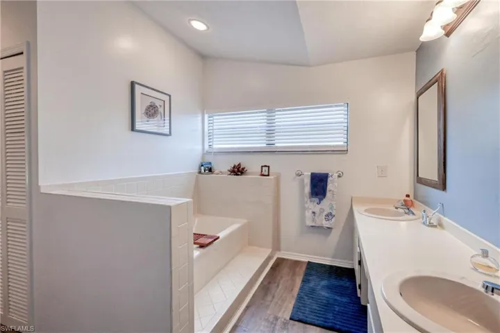 Bathroom with a tub to relax in, vanity, and wood-type flooring