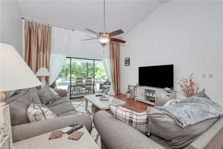 Living room with light wood-type flooring, high vaulted ceiling, and ceiling fan