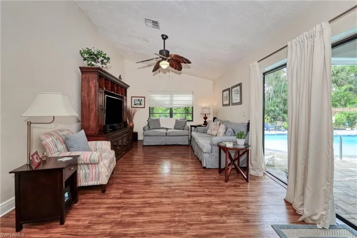 Living room featuring a healthy amount of sunlight, vaulted ceiling, ceiling fan, and dark hardwood / wood-style flooring