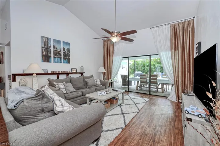 Living room with lofted ceiling, ceiling fan, and hardwood / wood-style flooring