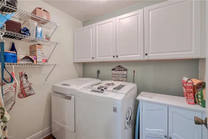 Washroom with cabinets and washer and clothes dryer