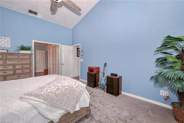 Carpeted bedroom with ceiling fan and high vaulted ceiling