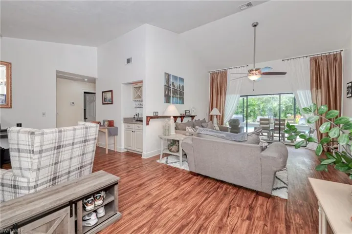 Living room with ceiling fan, hardwood / wood-style floors, and high vaulted ceiling
