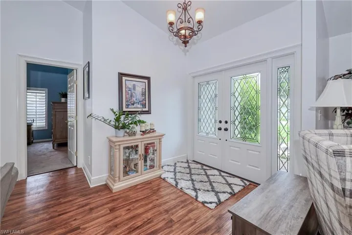 Entryway featuring an inviting chandelier, high vaulted ceiling, and dark hardwood / wood-style flooring
