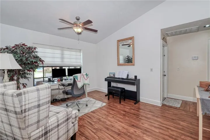 Home office with ceiling fan, hardwood / wood-style flooring, and vaulted ceiling
