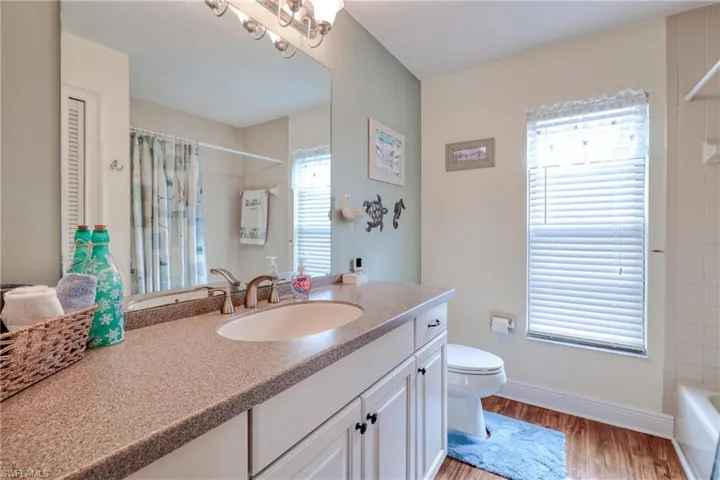 Full bathroom with vanity, toilet, hardwood / wood-style floors, and shower / bath combination with curtain