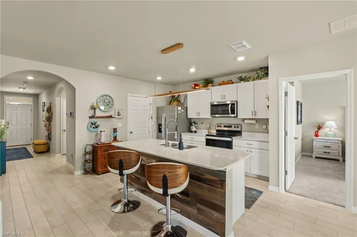 Kitchen featuring a breakfast bar, a sink, arched walkways, visible vents, and appliances with stainless steel finishes
