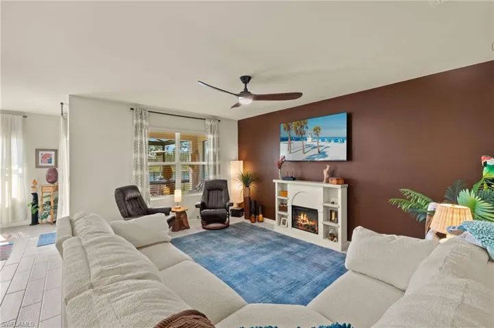 Living area featuring baseboards, a lit fireplace, an accent wall, and a ceiling fan