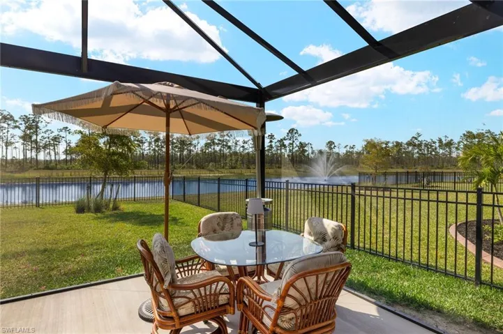 View of patio with a fenced backyard, outdoor dining space, a lanai, and a water view